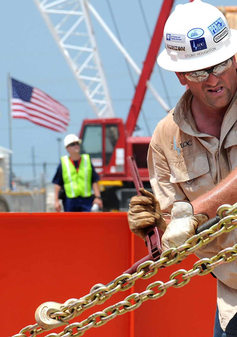 A worker in a hardhat working with a large chain